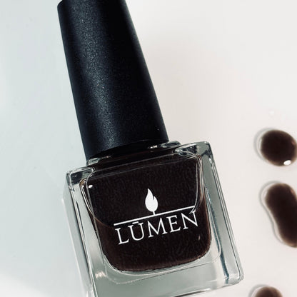 LUMEN nail polish bottle with black cap, dark espresso-brown polish in glass.