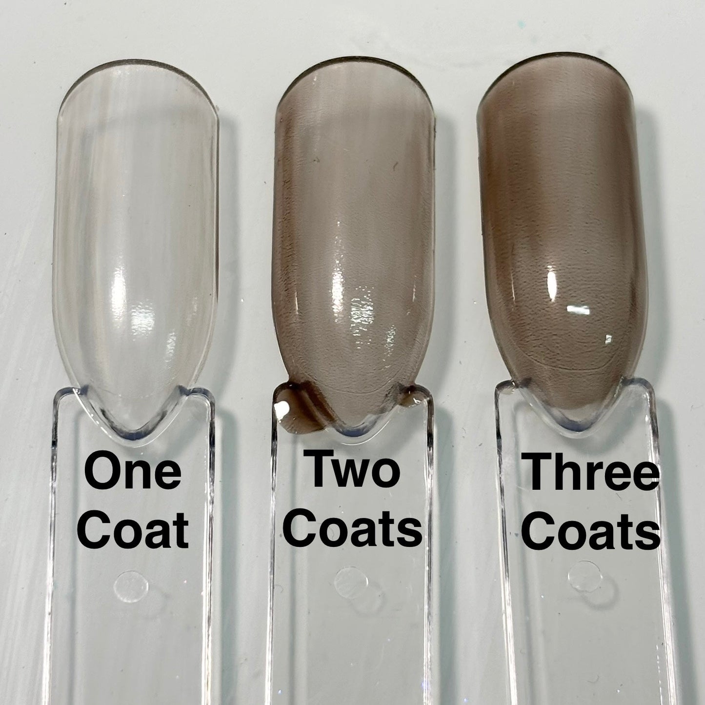 Nail polish coat samples showing light to deeper brown from one to three coats.