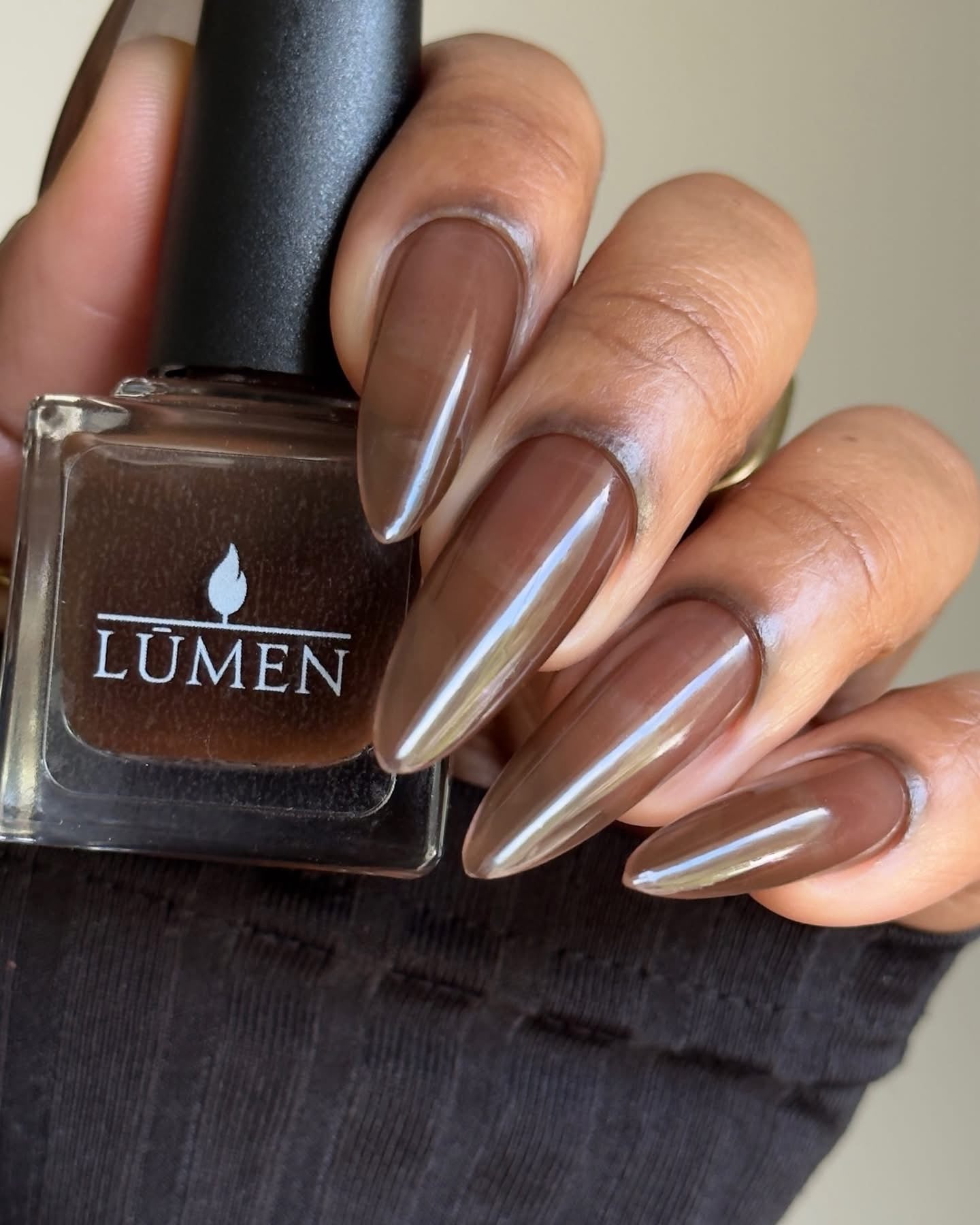 LUMEN nail polish bottle with dark espresso-brown shade and glossy long almond nails.