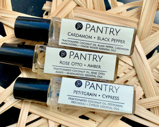 Essential oil perfume bottles with scent labels: cardamom, black pepper, rose otto, amber
