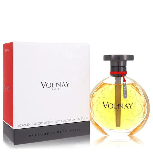 Women’s perfume bottle with dark cap and red collar, next to Volnay box on reflective base