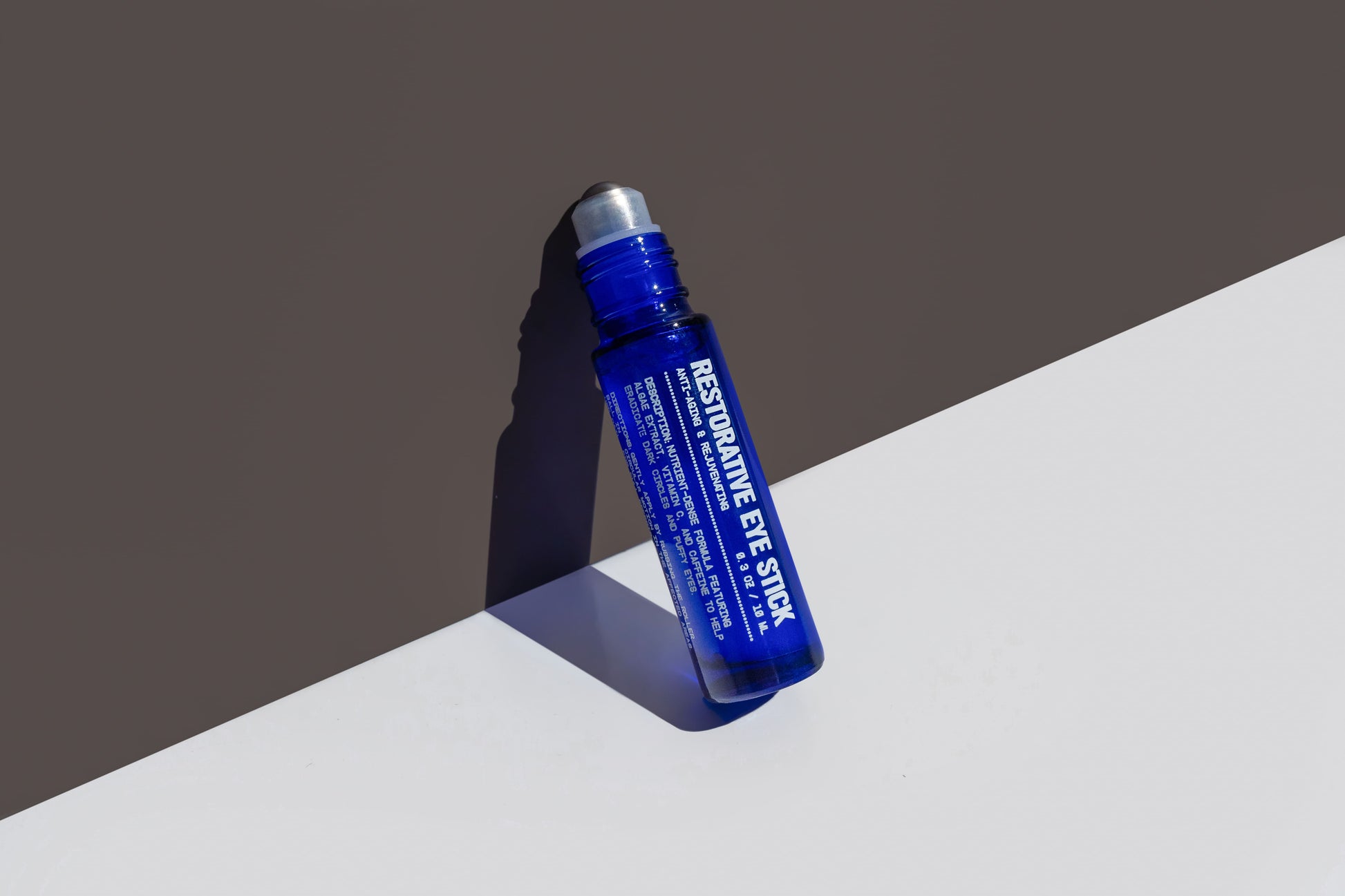 Restorative eye stick, blue tube with dark cap, angled view