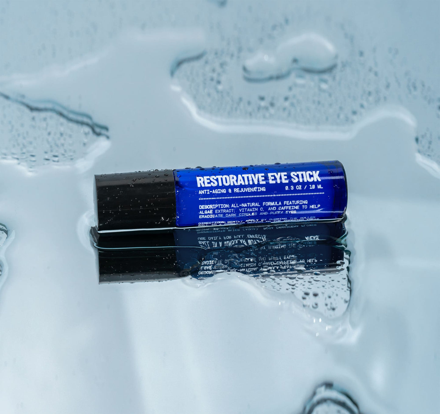 Restorative eye stick and cap, blue label on dark tube with liquid splash