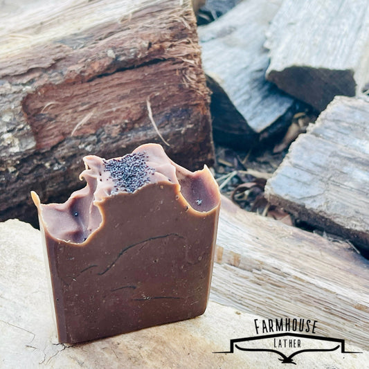 Brown soap bar with blue speckles and wavy cutouts, shown on a stone surface