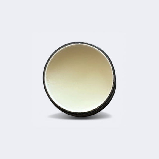 Tallow lip balm tin lid with pale balm visible in the opening