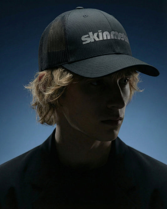 Dark trucker hat with mesh back, stitched curved brim, 'skinmetal' logo