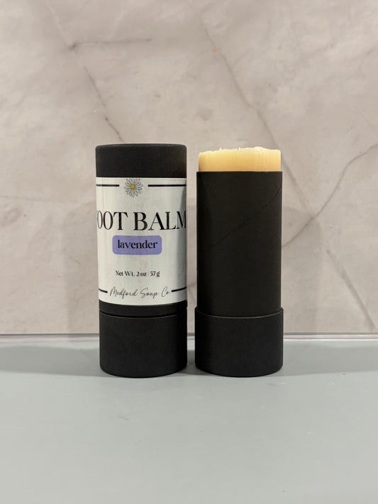 Foot balm stick in black tube, labeled lavender, with pale cream bar top
