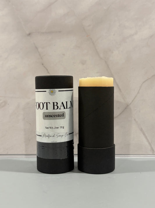 Foot balm stick in black tube, labeled unscented, with pale cream bar top