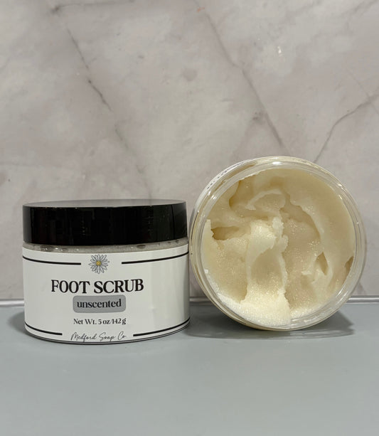 Foot scrub jar with black lid; unscented label; pale cream scrub in open container.