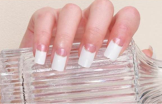 French gel manicure nails with white tips and nude-pink base on a hand