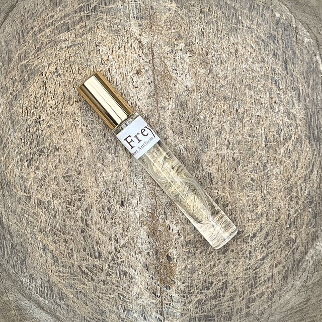 Freyja perfume spray bottle lying down, gold cap on clear glass
