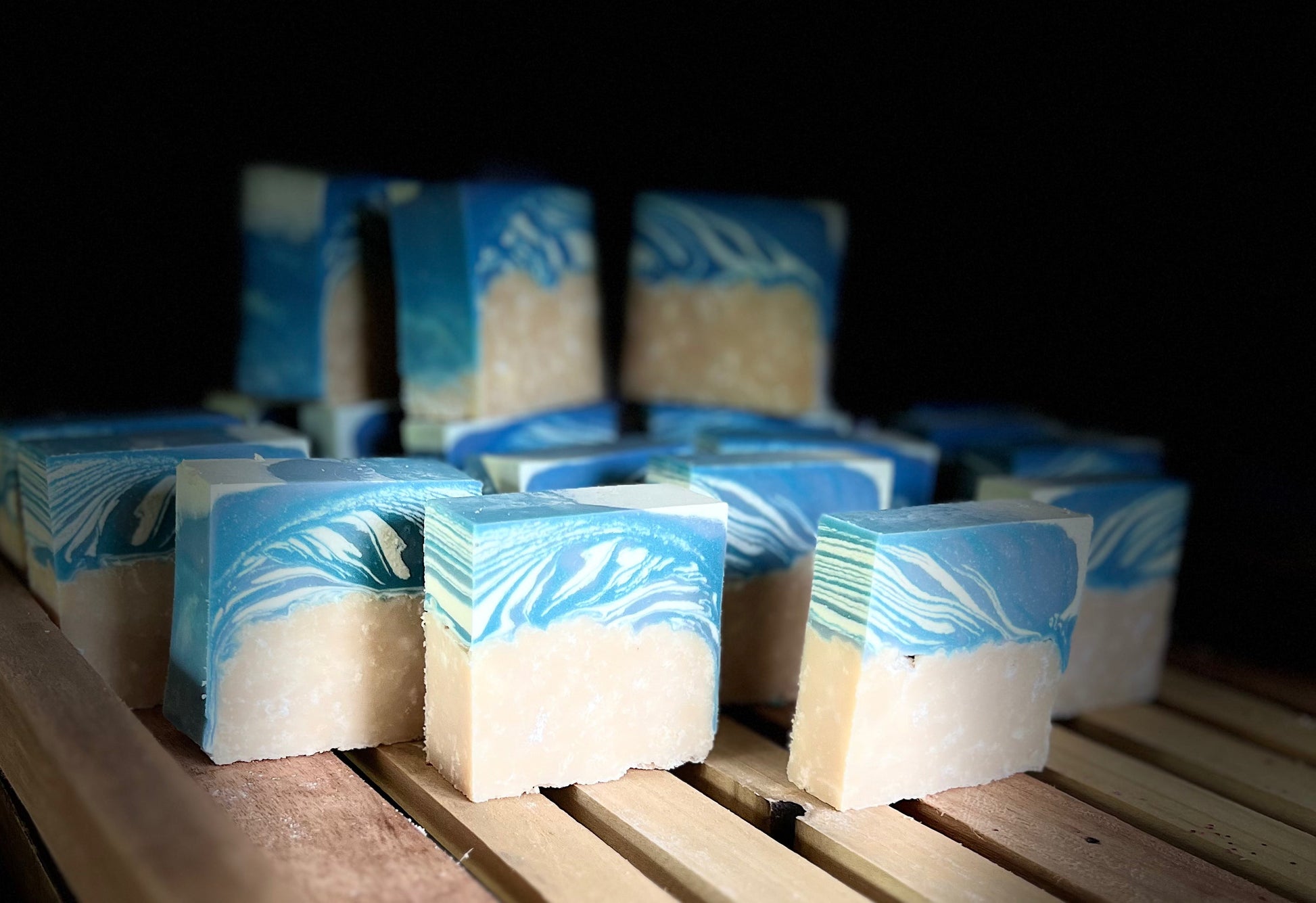 Goat milk soap bars with blue and cream swirl tops, stacked on wooden tray