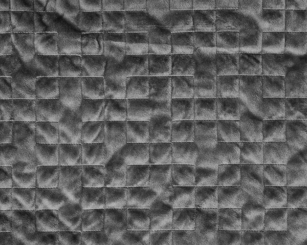 Close-up of grey quilted weighted blanket fabric with raised square pattern