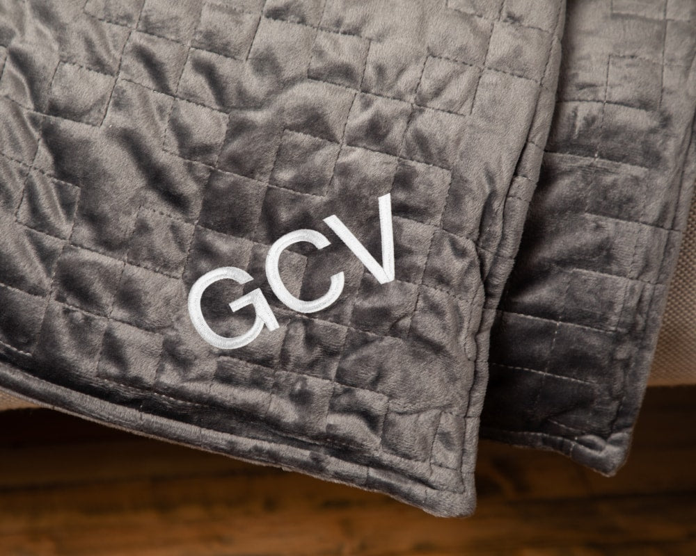 Grey weighted blanket corner with quilted stitching and GCV logo patch