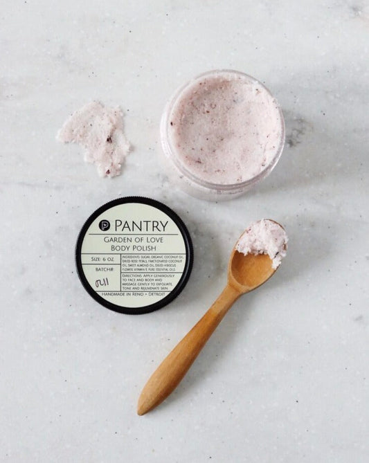 Exfoliating body polish jar with pink sugar scrub and wooden spoon scoop
