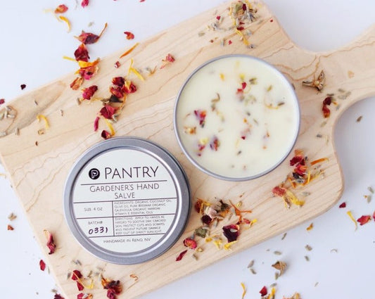 Round herbal hand salve balm tin with cream balm and lid, with scattered dried petals