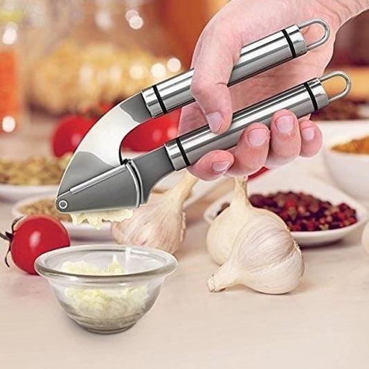 Garlic press with stainless handles crushing garlic cloves and peels into a bowl