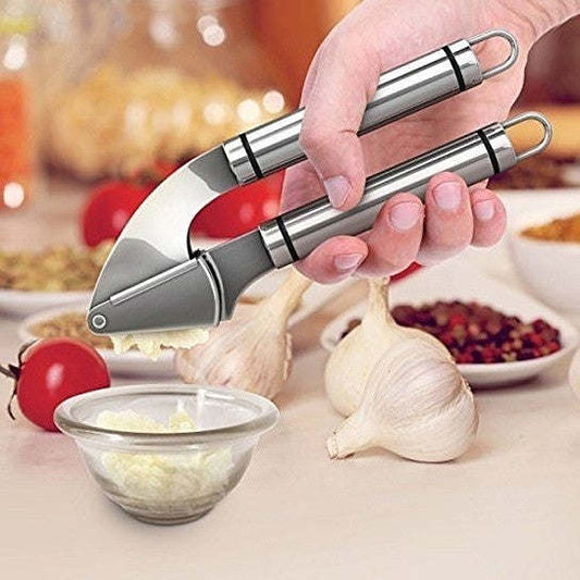 Garlic press held in hand over a bowl of chopped garlic and garlic cloves