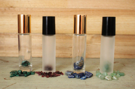 Clear frosted gemstone roller bottles with gold and black lids, with mixed green, red, blue stones