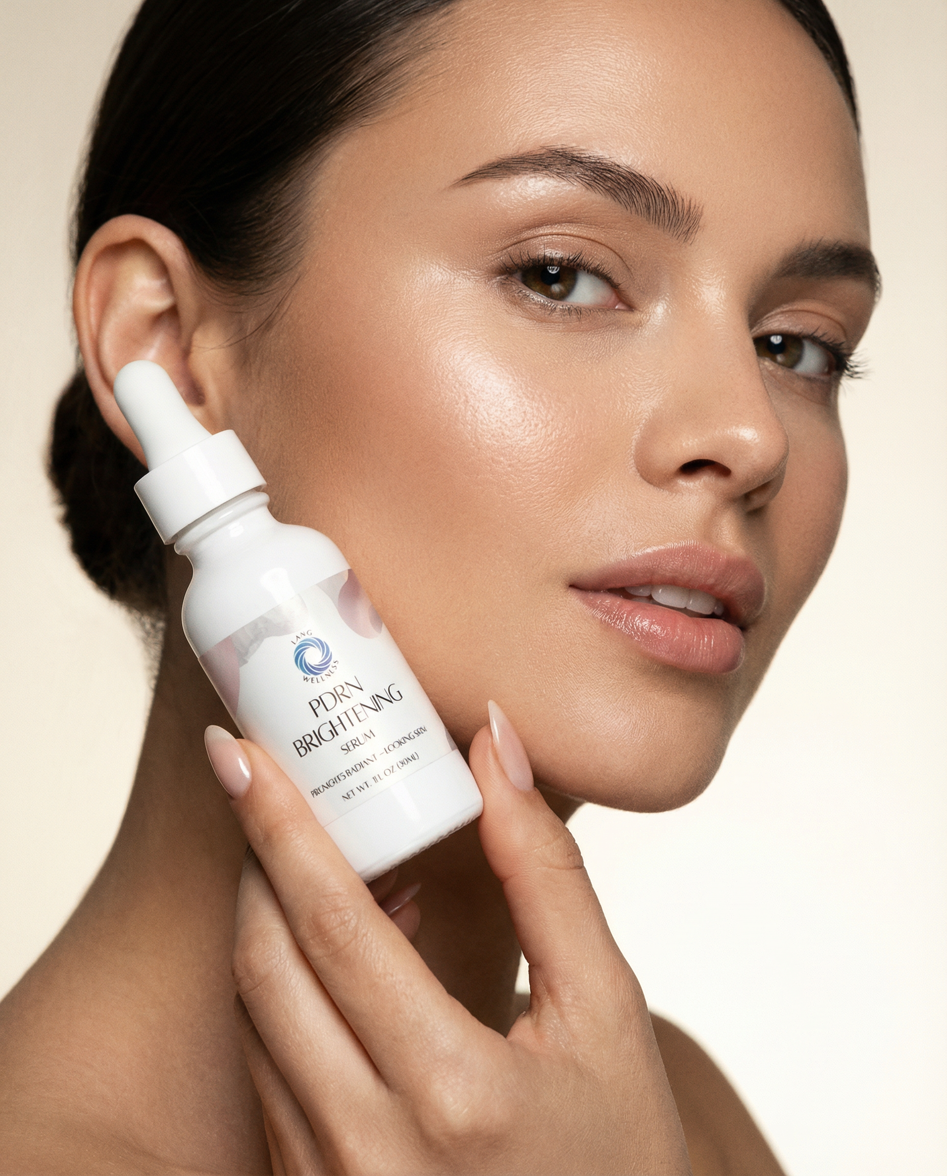 Brightening serum bottle held near cheek; white dropper and label on clear glass