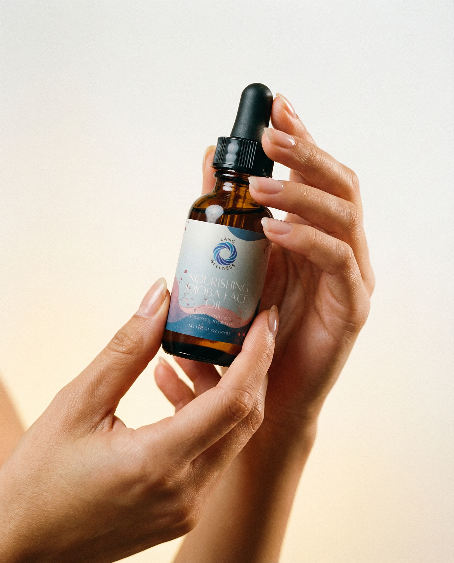 Hands holding jojoba face oil bottle with dropper, amber glass
