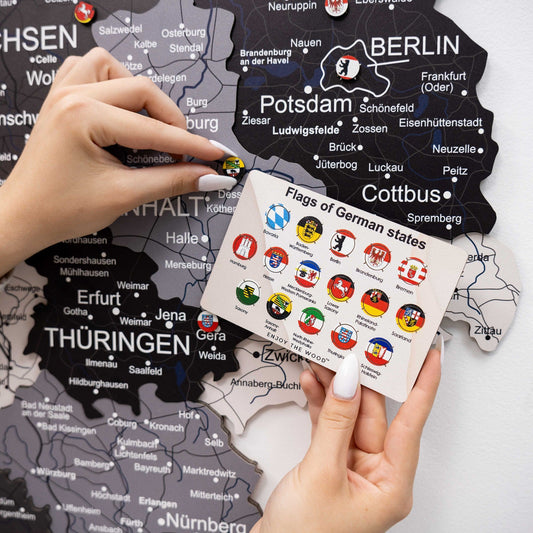 Hand holding German state flag pin card with 16 round flag emblems