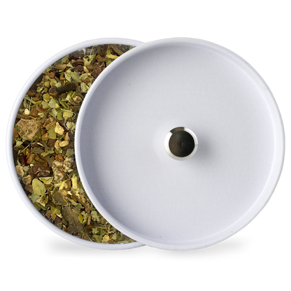 White-lidded container with opening, showing loose herbal tea leaves beside it