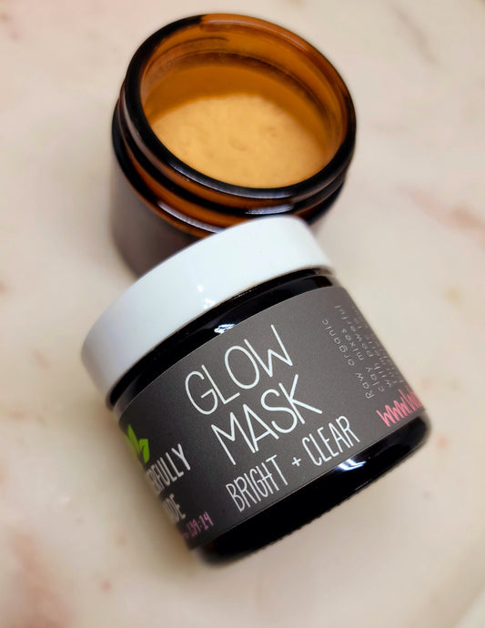 Turmeric clay face mask jar with black label and white lid, golden cream inside