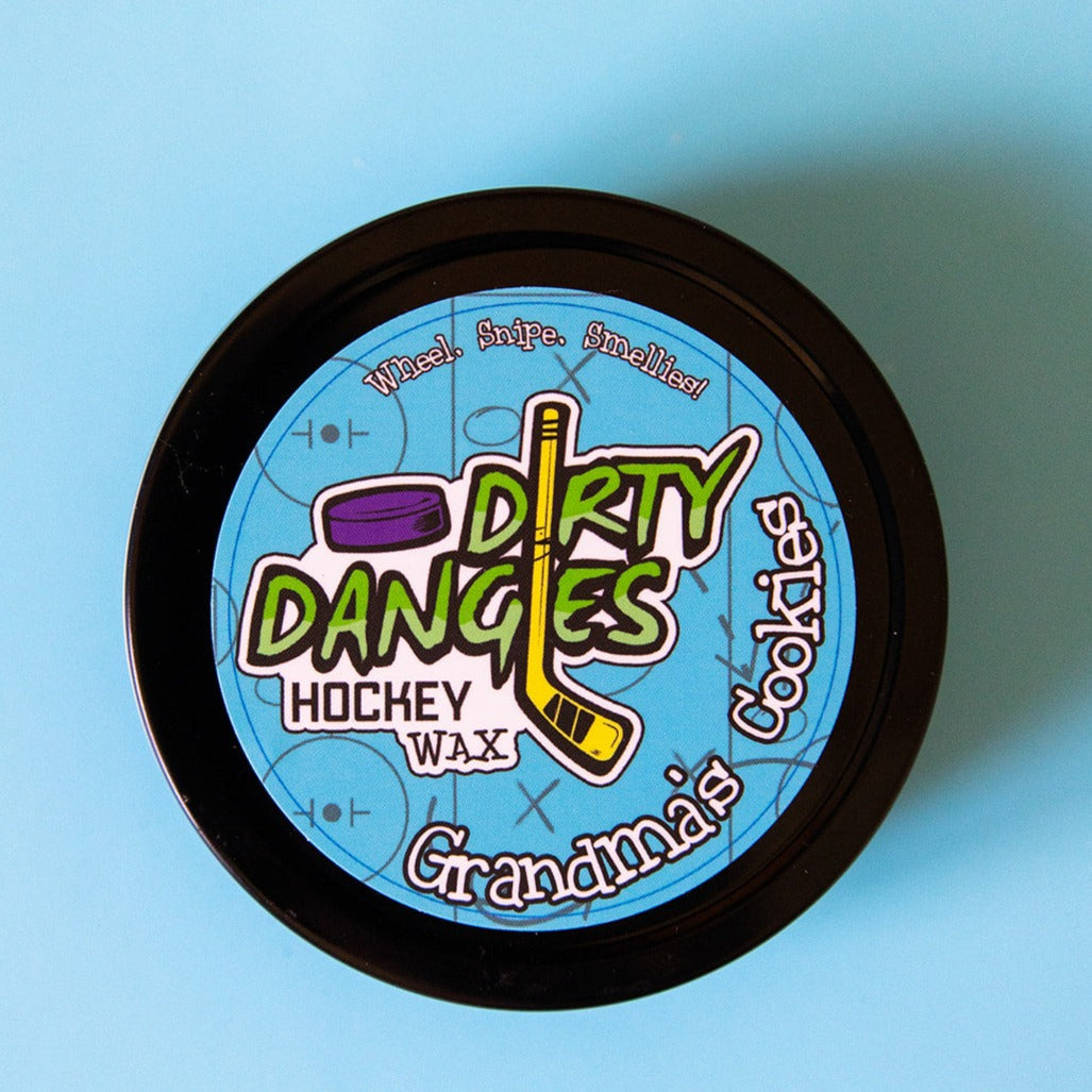 Hockey stick wax tin close-up with 'Dirty Dangles Hockey Wax' blue graphic label