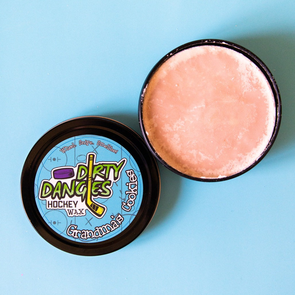 Hockey stick wax tin with lid open, showing pink wax disc and 'Dirty Dangles' label