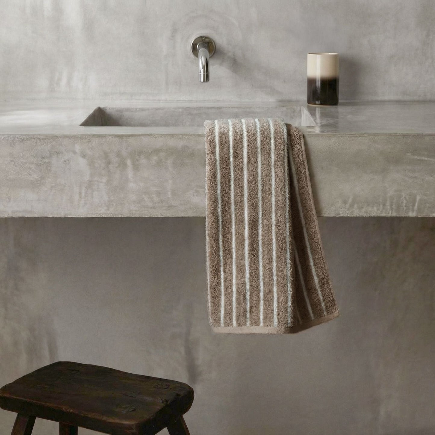 Striped towel hanging on bathroom bar, beige and white plush cotton loops