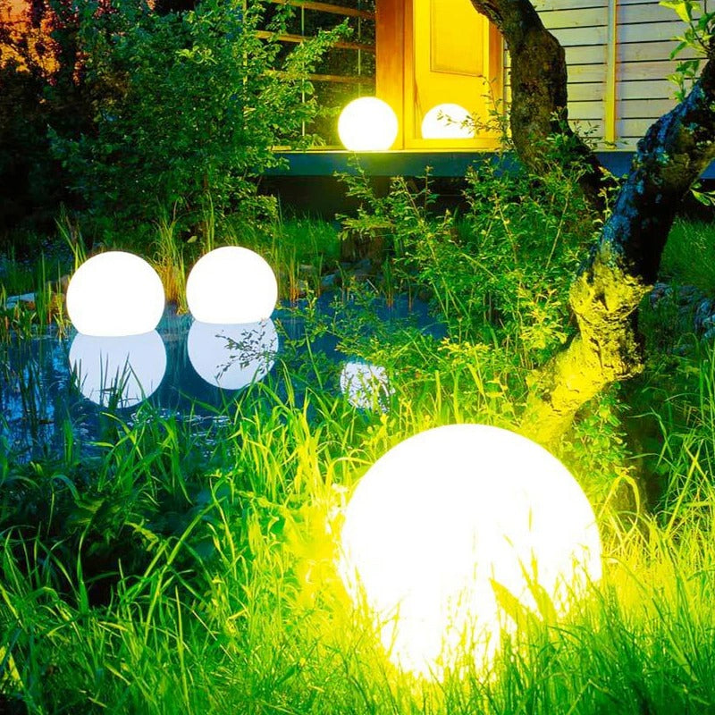 Garden LED garden ball lights with bright white glowing spheres along green grass at night