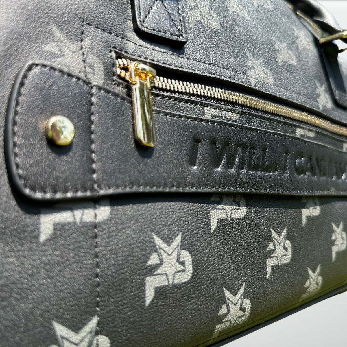 Black leather duffel bag close-up of gold zipper and stitched logo patch