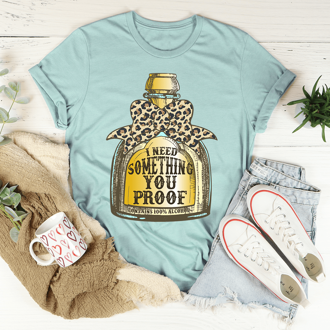 Dusty blue T-shirt with leopard bottle graphic and I NEED SOMETHING YOU PROOF text.