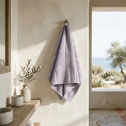 Lilac bath towel folded and hanging, with a neatly finished edge.