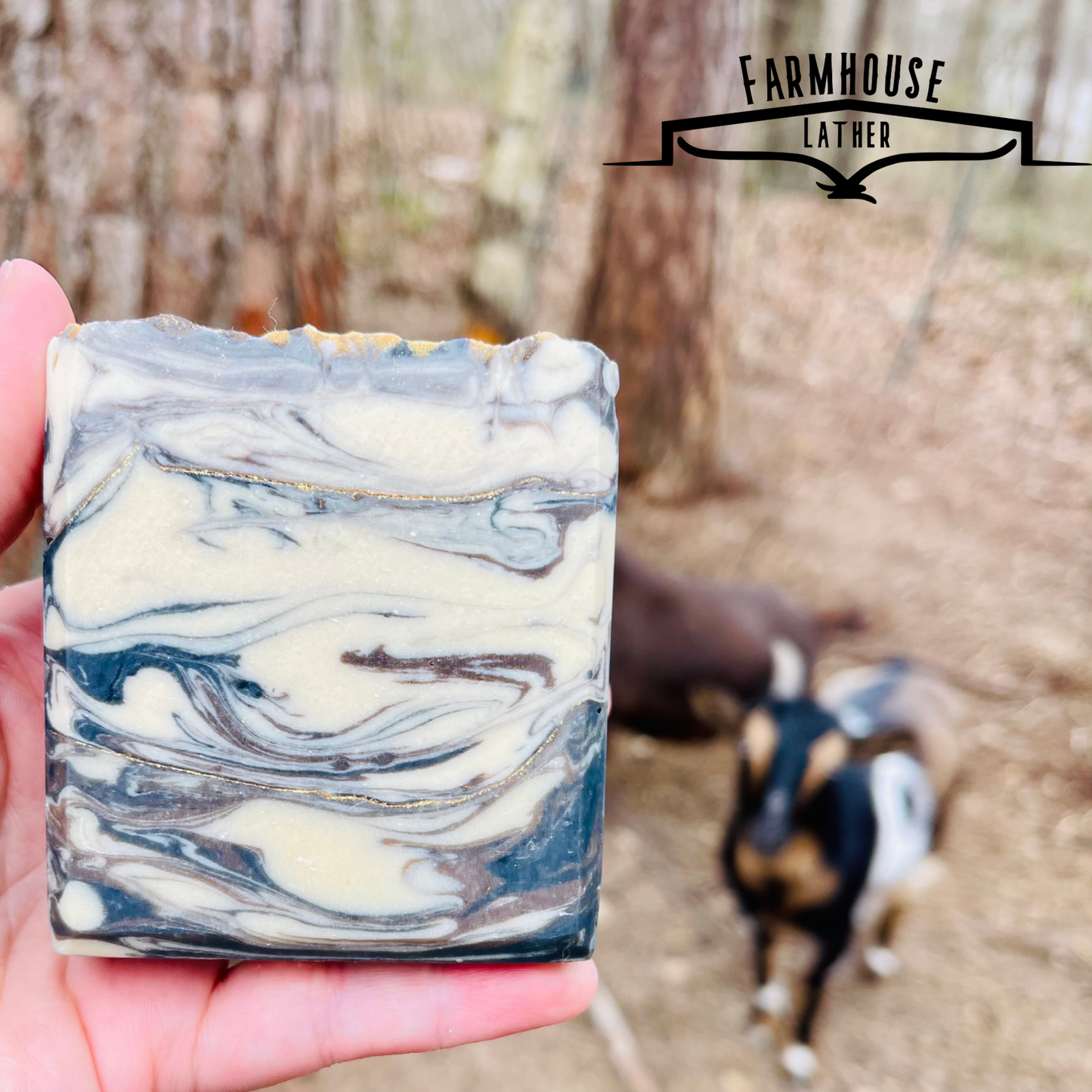 Marbled bar soap with white, blue, and gold swirls, held in hand