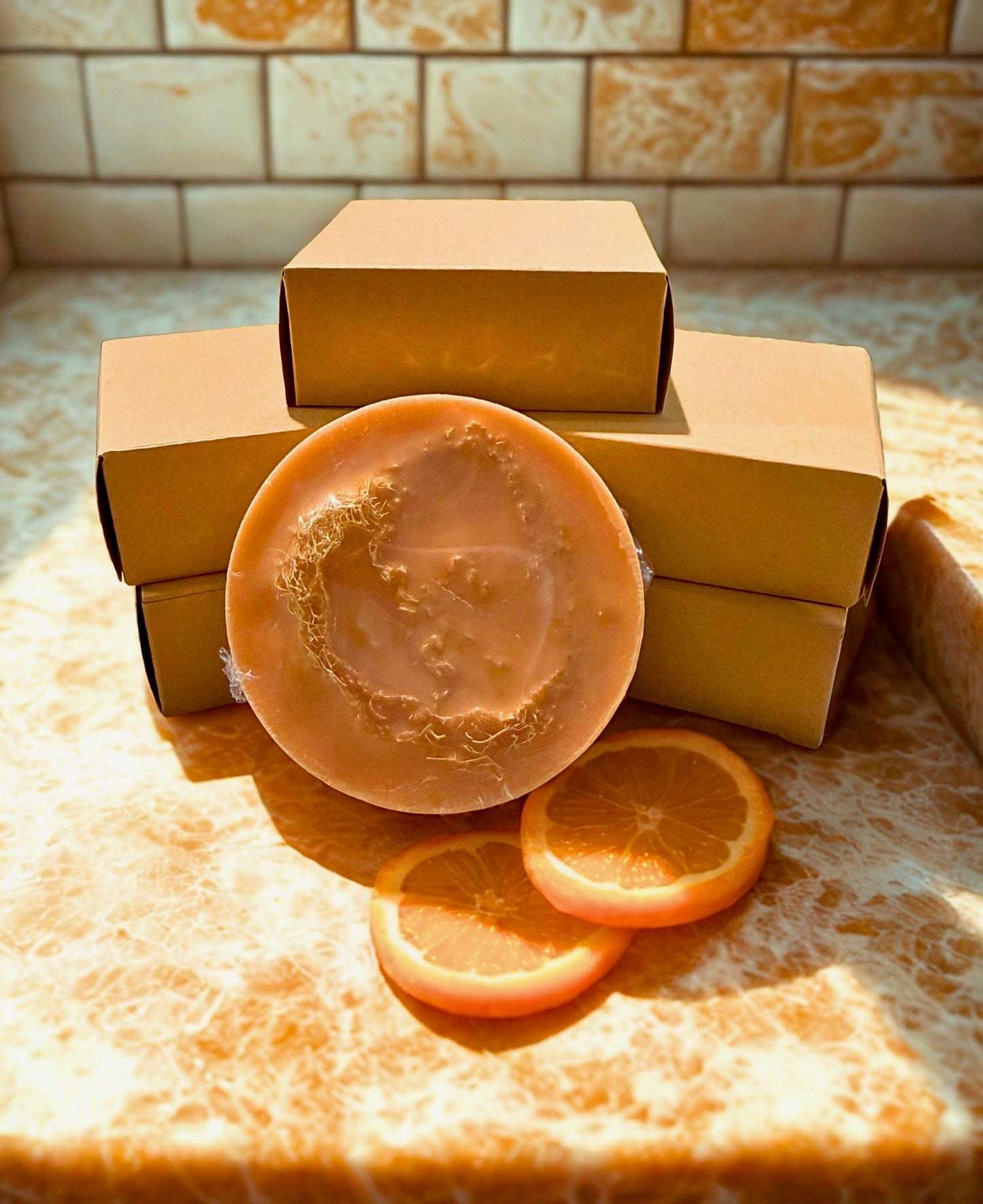 Orange handmade soap bar with embossed top, resting on open cardboard boxes