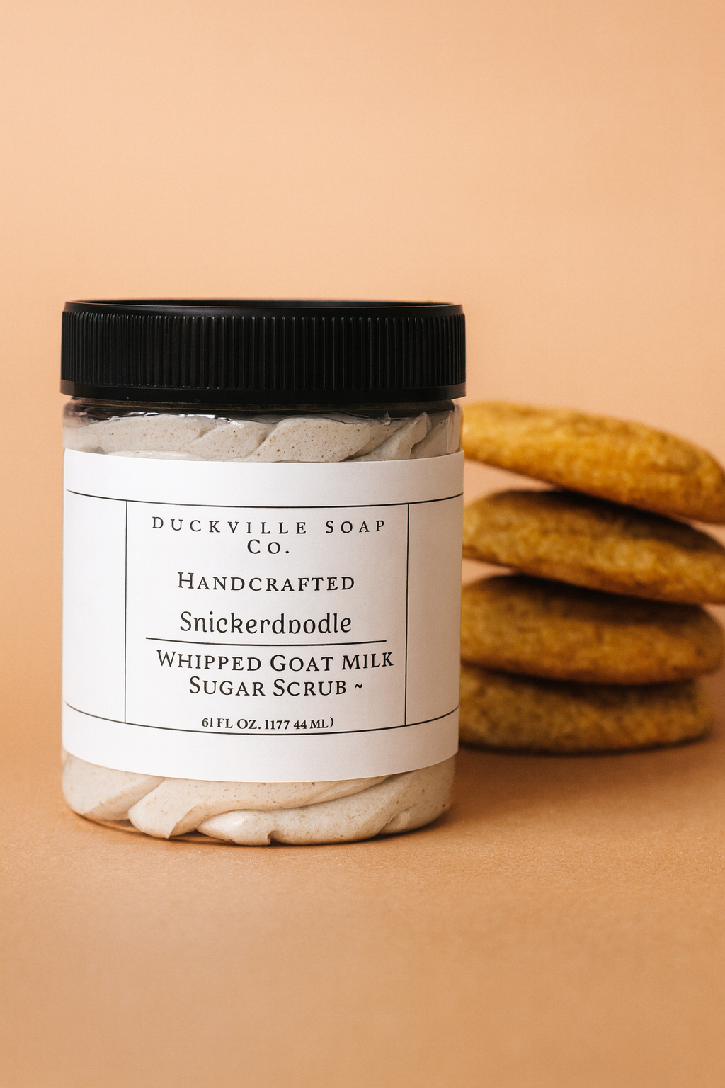 Whipped goat milk sugar scrub jar, Snickerdoodle label, black lid, beige flakes