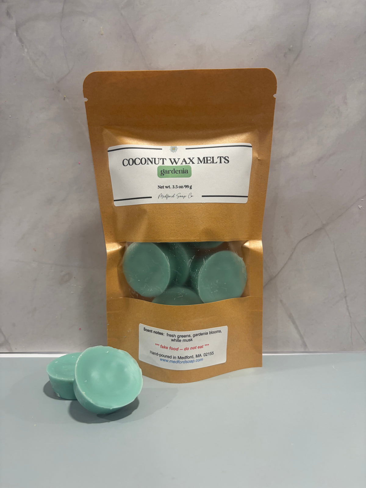 Coconut wax melt bag with teal wax cubes, plus one loose teal melt.