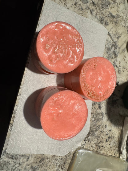 Pink round soap bars on a folded paper towel over stone tile