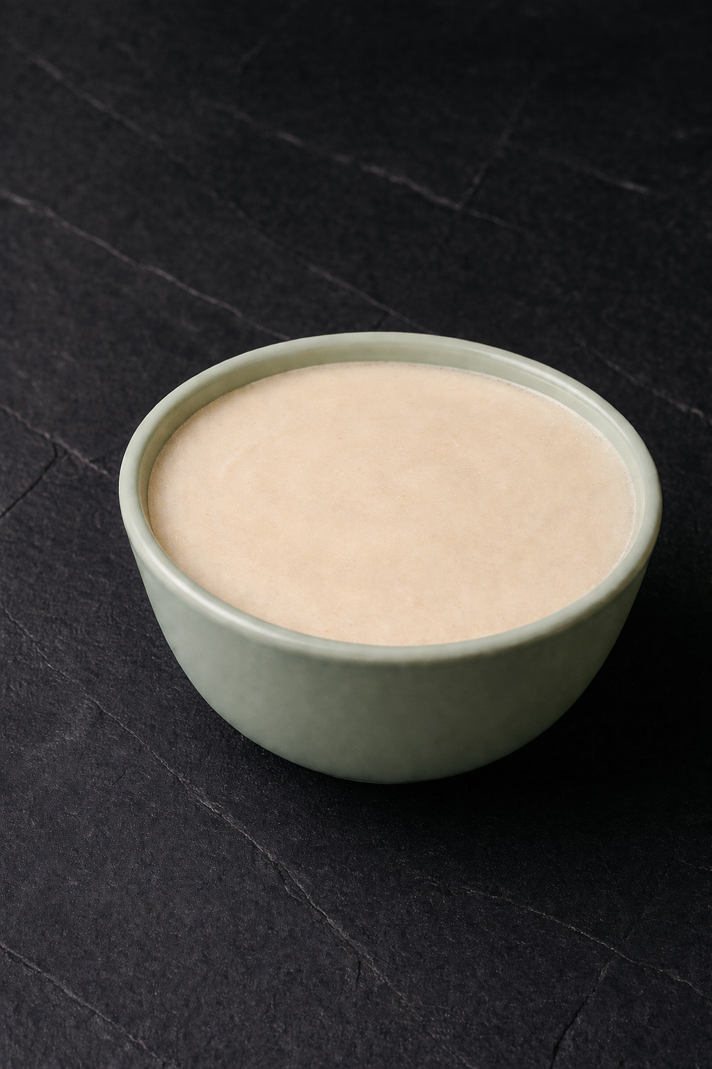 Shave soap tub with pale cream soap top inside a light green bowl