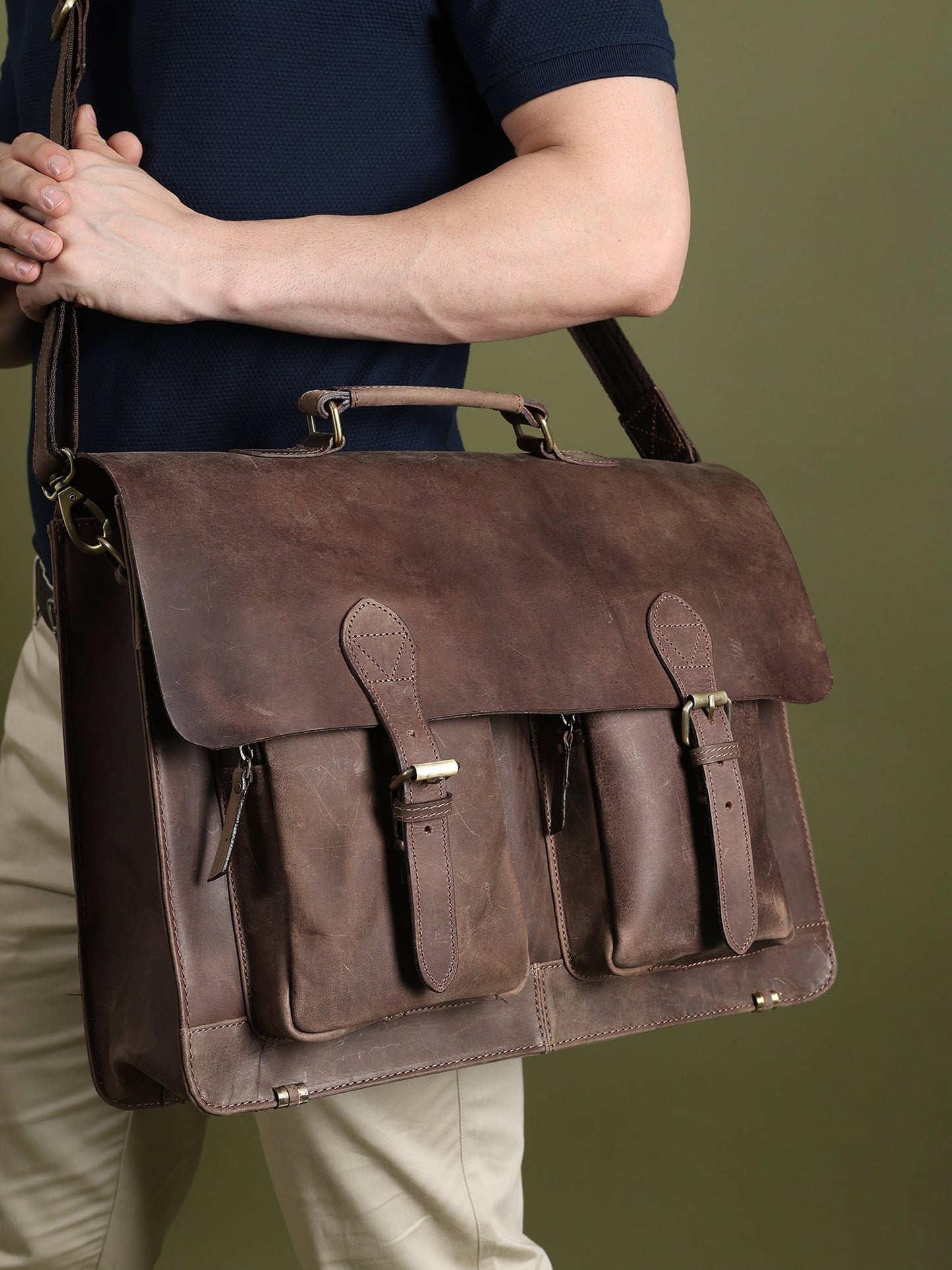 Brown buffalo leather messenger bag with flap, multiple front pockets, and adjustable shoulder strap.