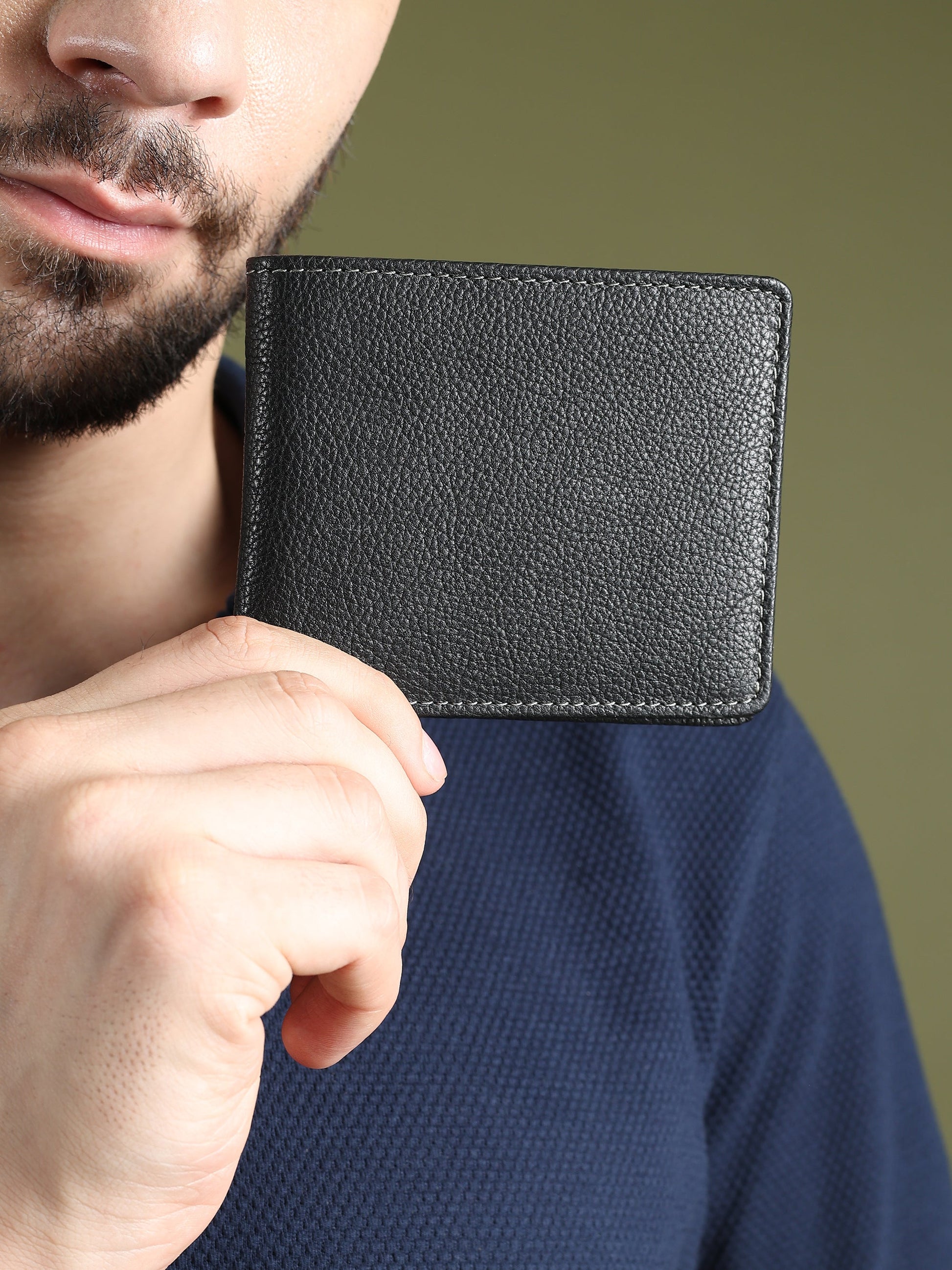 Black textured leather men’s wallet held near chest, compact bi-fold