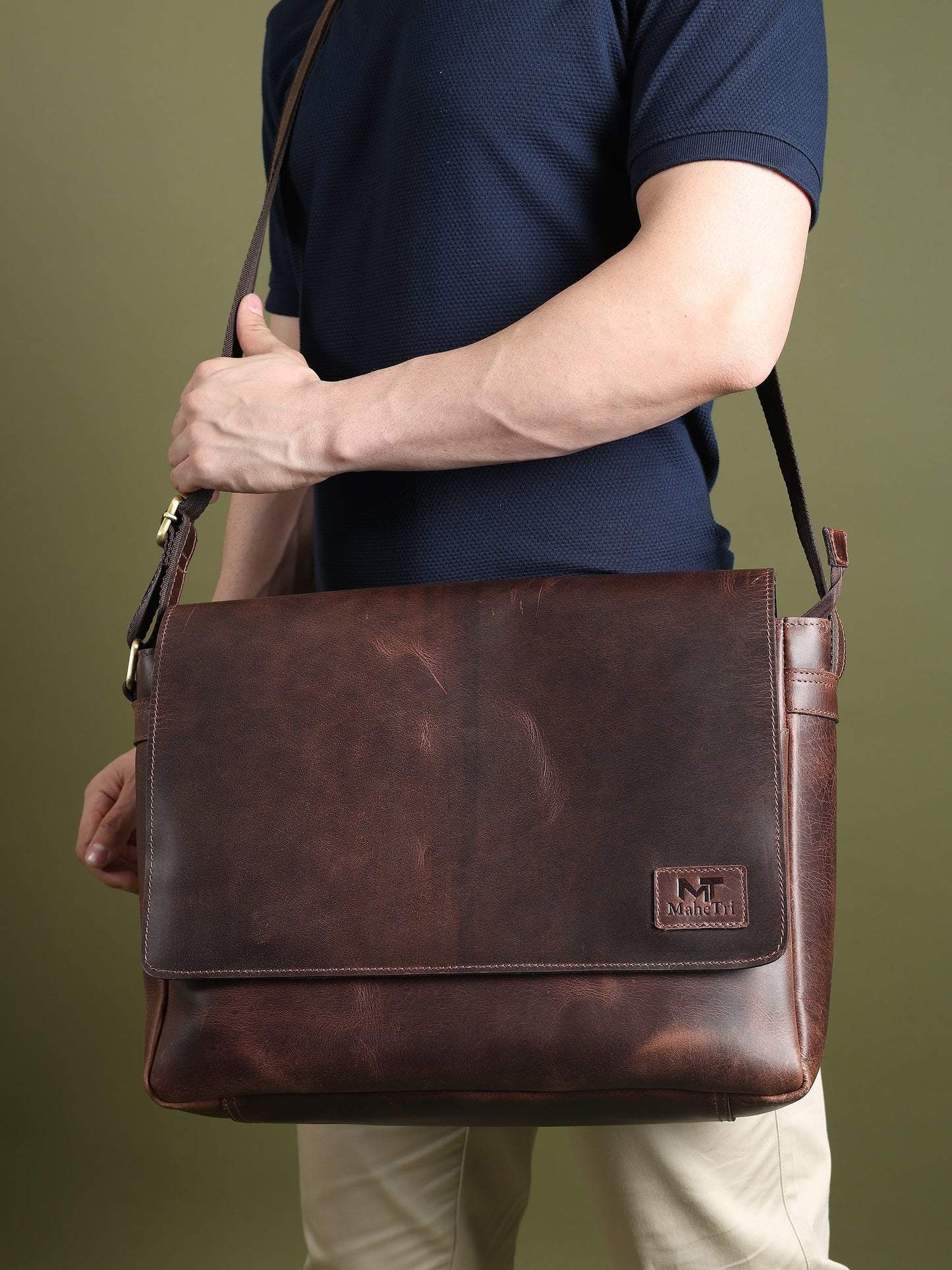 Brown leather laptop messenger bag carried at side with front flap