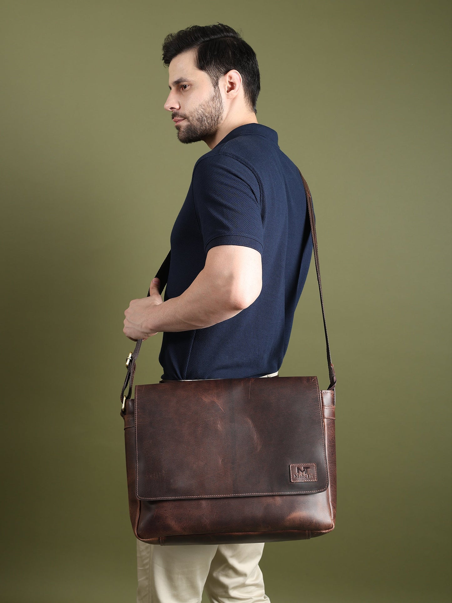 Brown leather laptop messenger bag on shoulder with front flap and logo patch