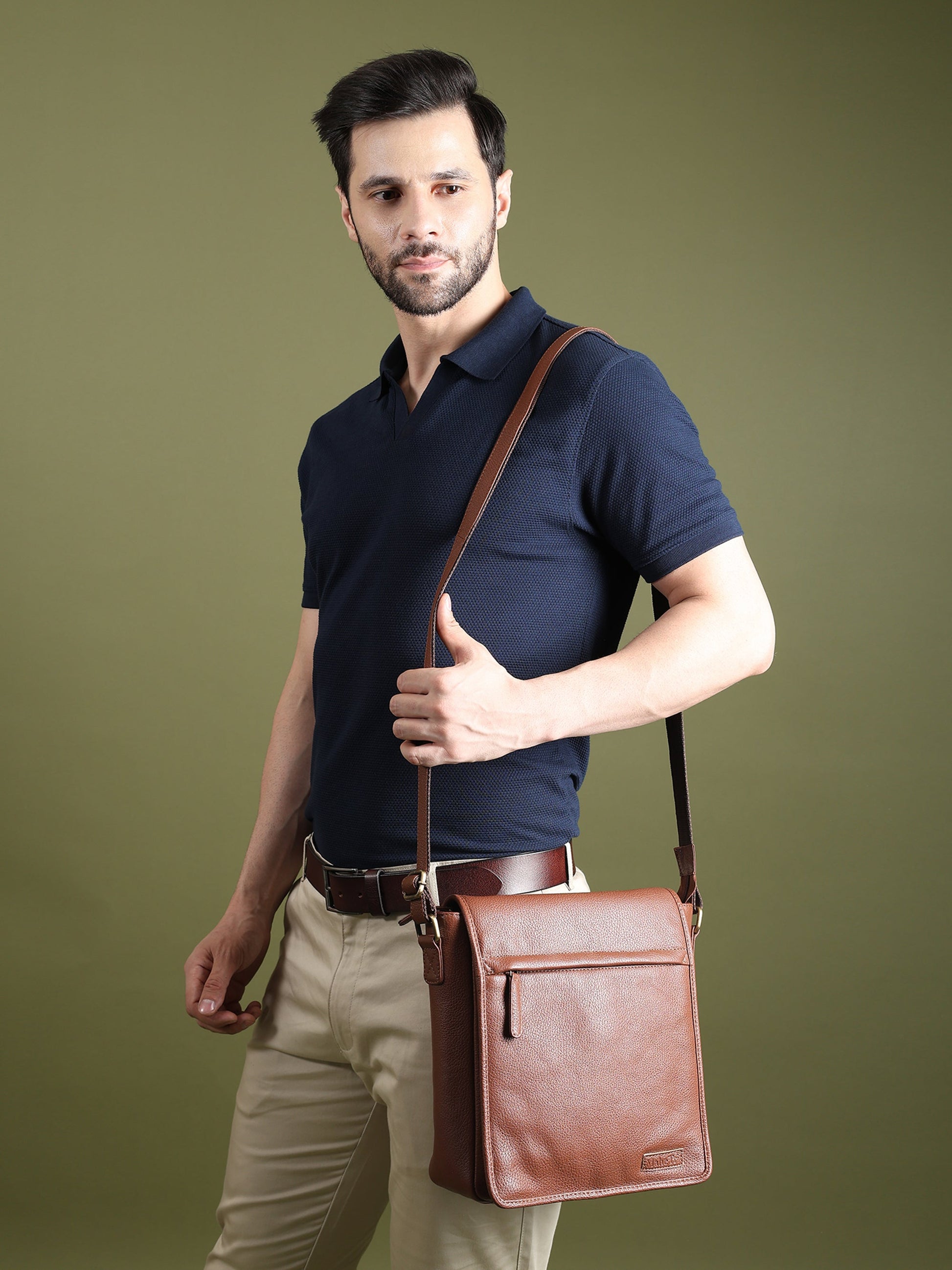 Brown leather crossbody bag worn on a person, with flap closure and shoulder strap