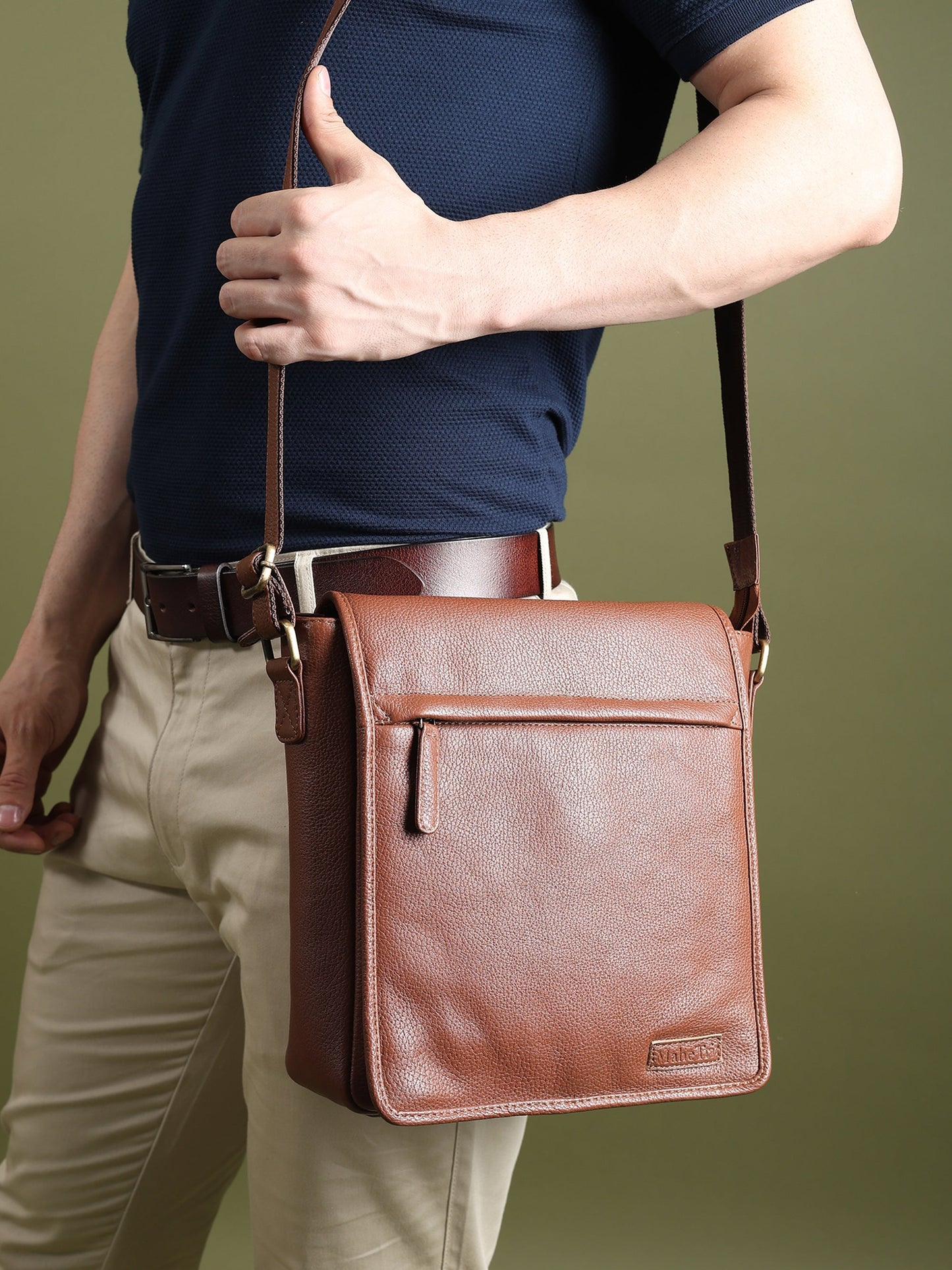 Brown leather crossbody bag worn, front flap with center seam and hanging tag detail