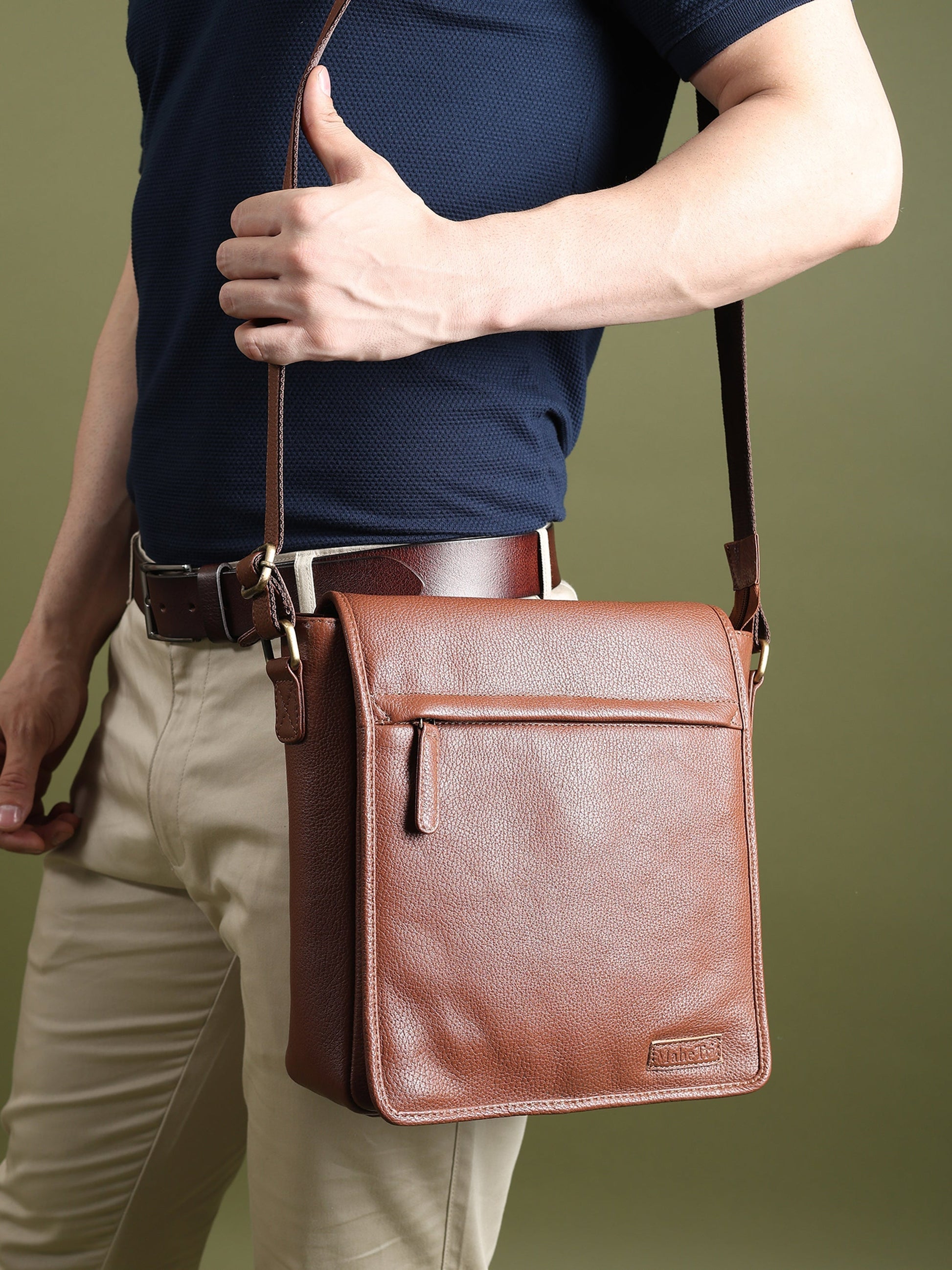Brown leather crossbody bag worn, front flap with center seam and hanging tag detail