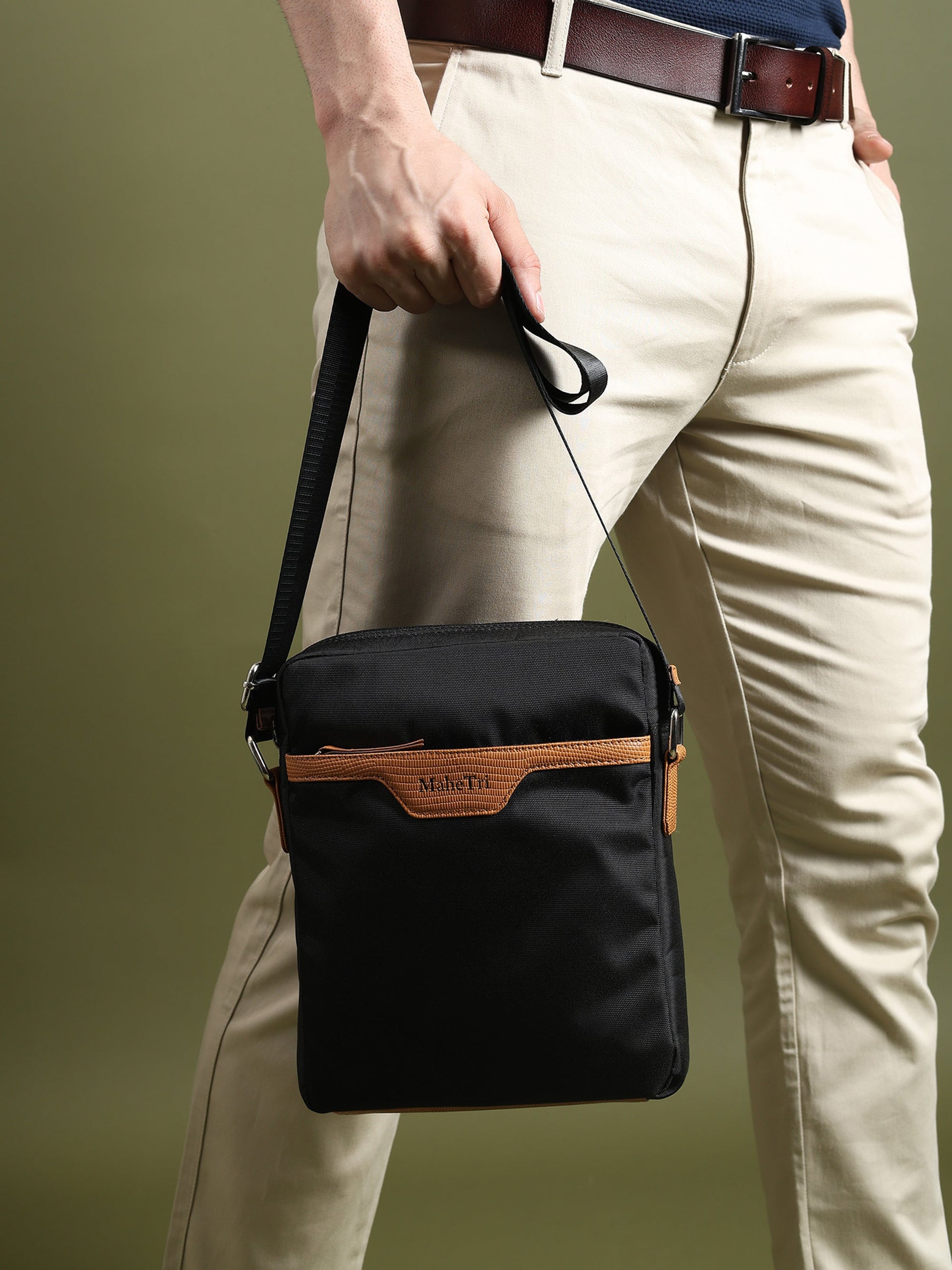 Black canvas side messenger bag with tan trim worn at hip with crossbody strap
