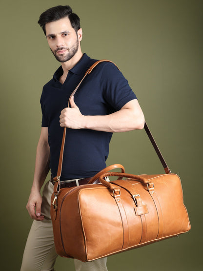 Tan leather duffle bag on a long shoulder strap, held by a model